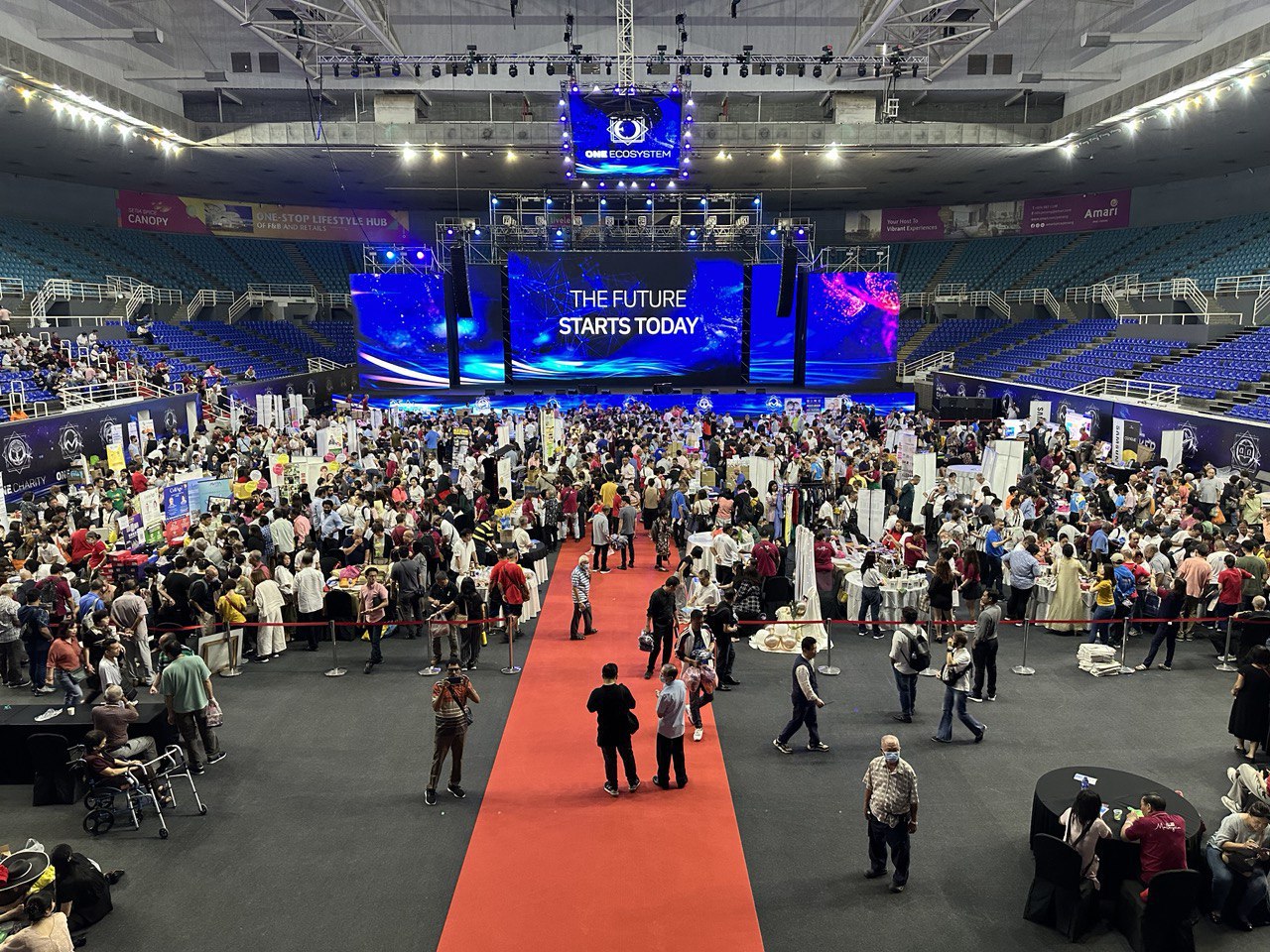 Un gran numero di persone si è riunito nell'arena dell'evento tecnologico e le parole "Il futuro inizia oggi" sono esposte al centro della scena.
